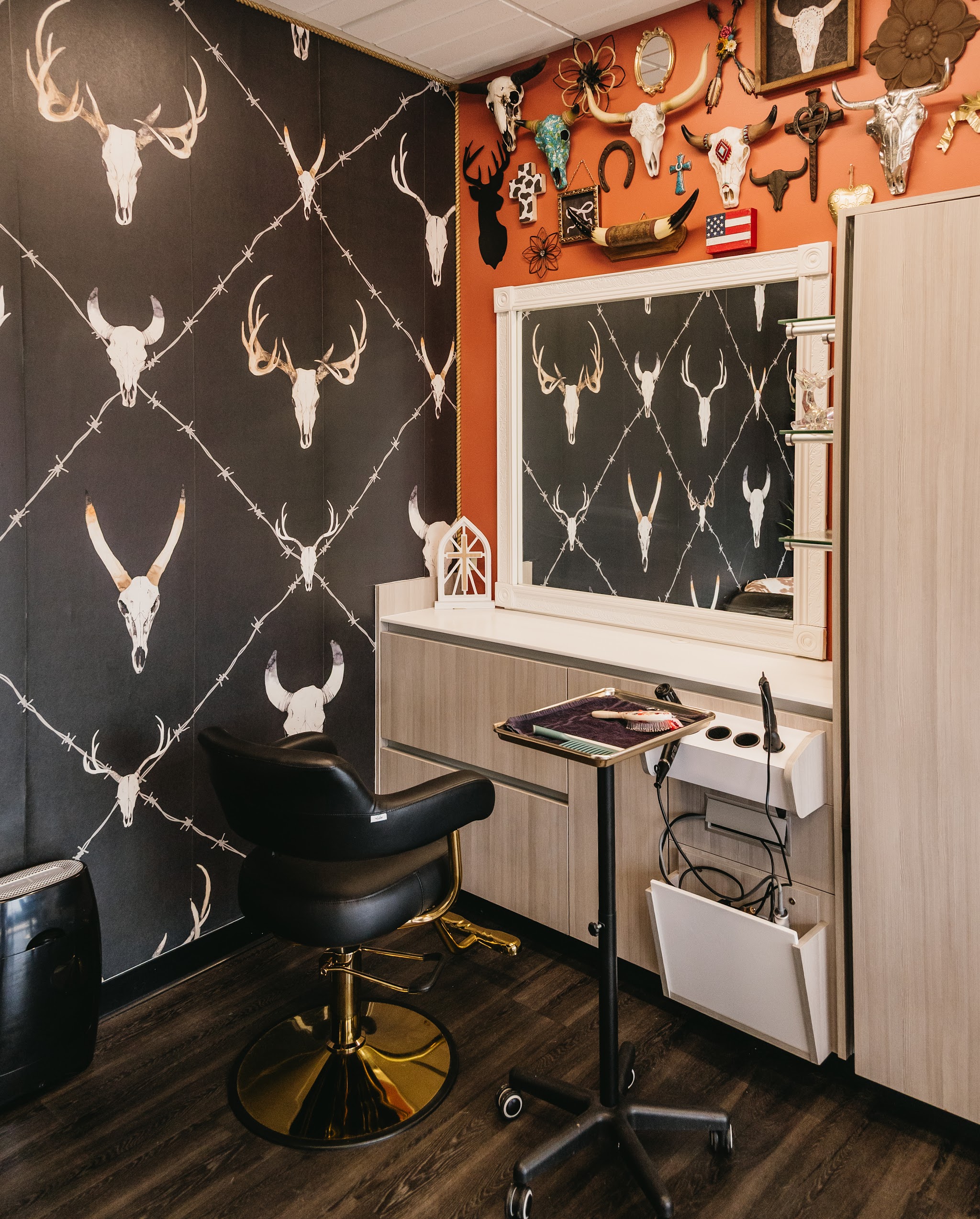 Our styling station with a black chair, gold base and an orange wall of horns