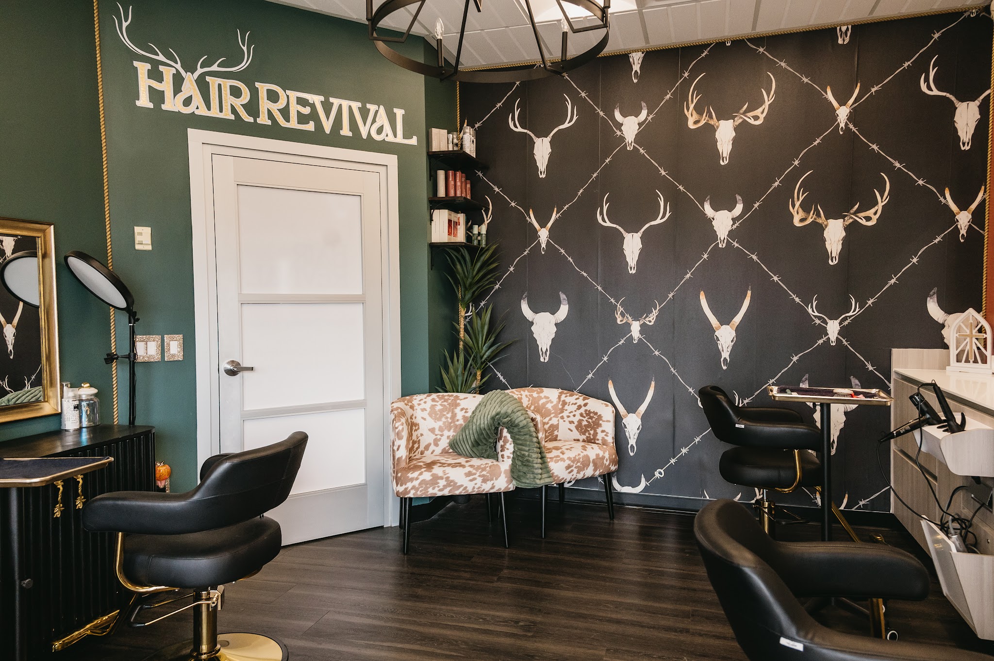Our studio: a green wall with the Hair Revival sign beside antler wallpaper and black salon chairs